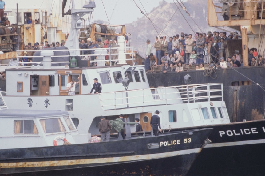 A police vessel stands guard alongside a freighter crammed with more than 3,000 Vietnamese refugees inside Hong Kong's harbor.