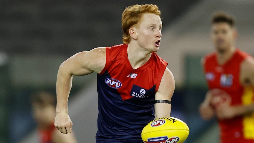 A Melbourne Demons AFL player prepares to handball to his left against the Gold Coast Suns.