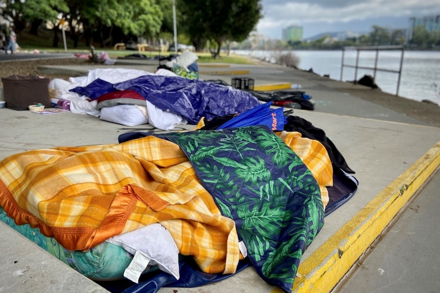 Sleeping bags and blankets set up on a concrete slab in the Brisbane CBD