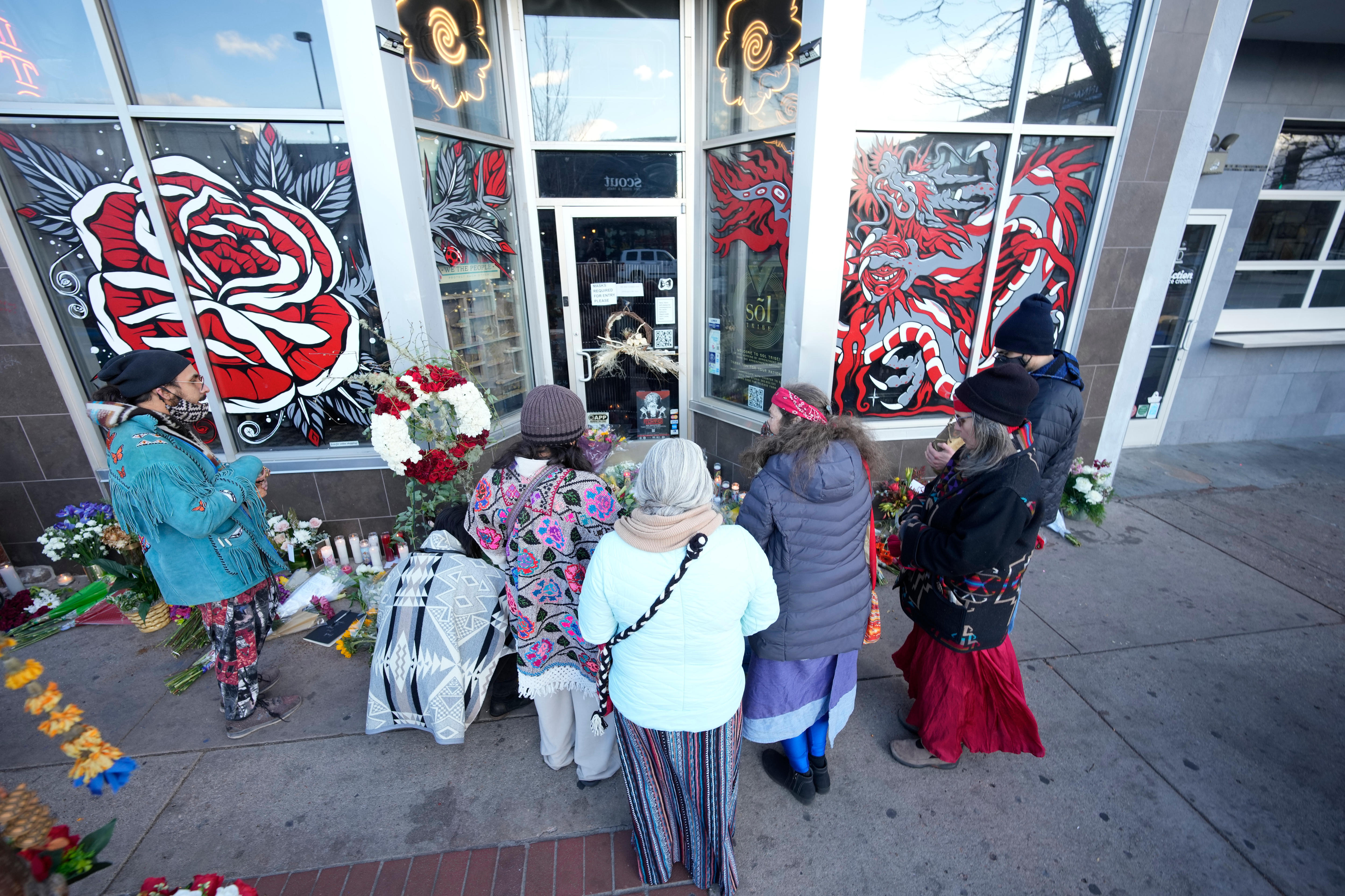 Mourners gather outside the door of a tattoo parlour. 