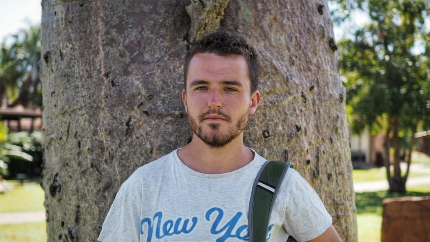 English backpacker Steven Browne pictured next to a boab tree in Kununurra. He's looking for harvest work.