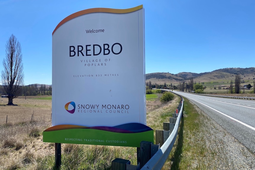 A sign that says "Bredbo" on the edge of a country road.