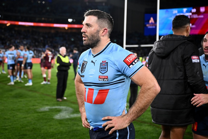 NSW player James Tedesco looks on after a match, with staff and media on the field