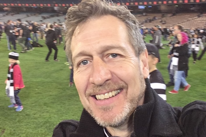 A man in a selfie-style photo in the ground of an AFL match after it had concluded.
