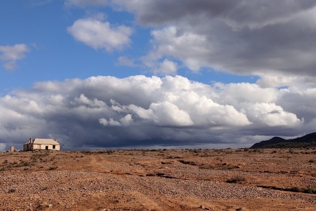 A homestead on a rural property beneath moody clouds.