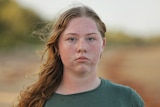 Young teen wearing a green shirt with her hair to the side.