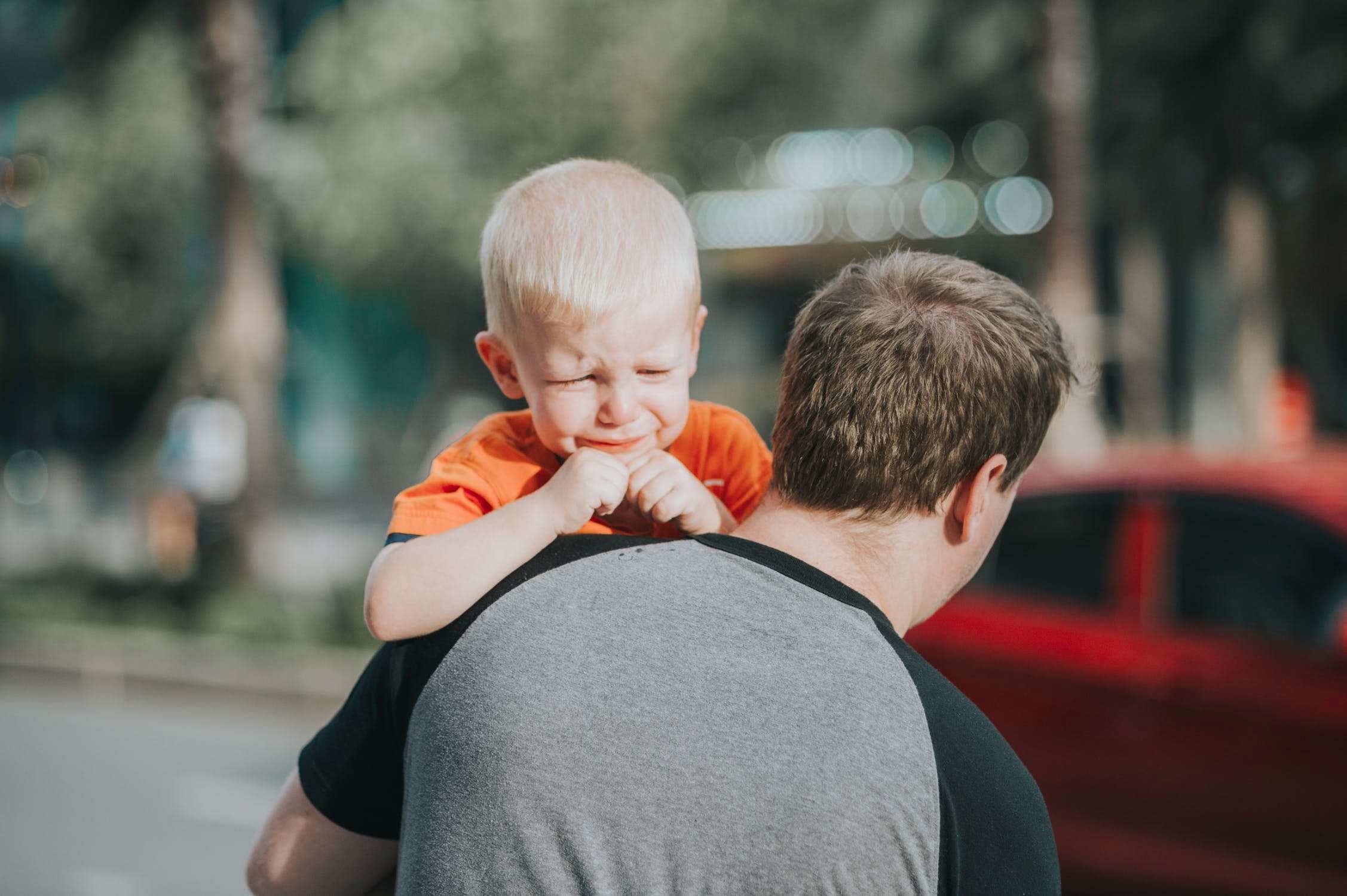 A young boy cries as he held by a man.