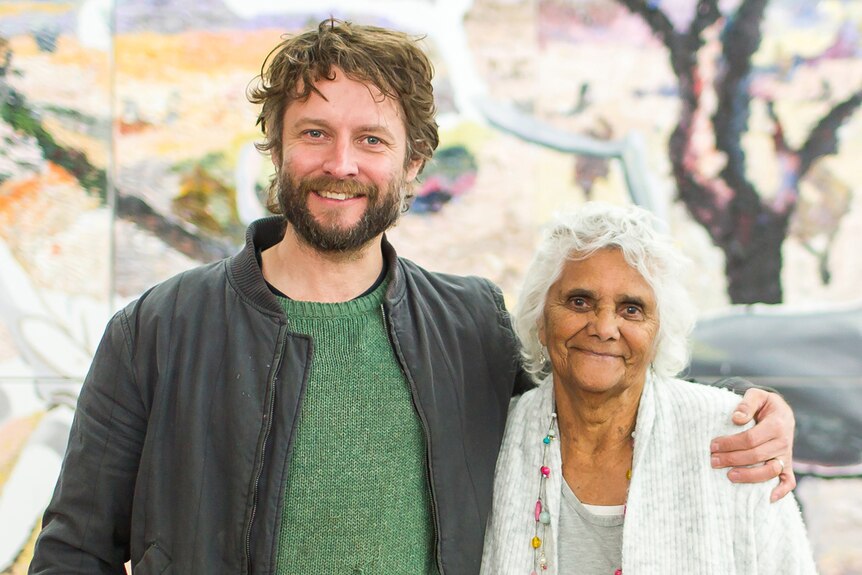 Man with short brown hair and beard with arm around smaller older woman with short white curly hair - both smiling.