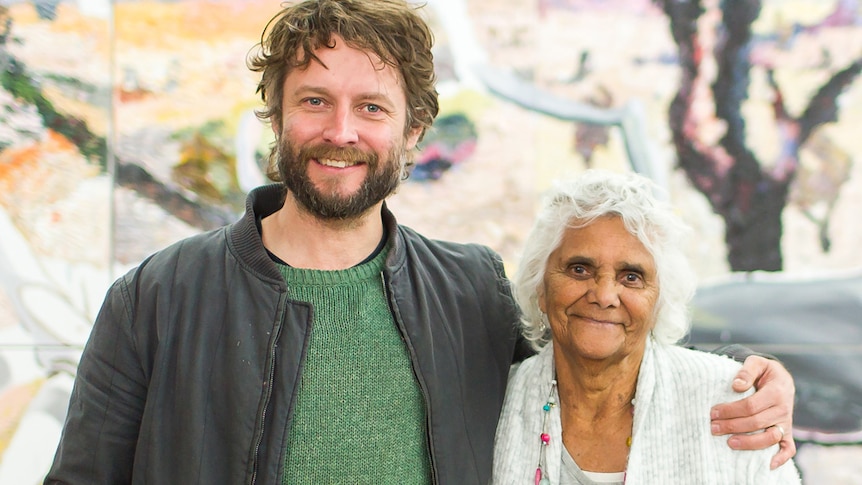 Man with short brown hair and beard with arm around smaller older woman with short white curly hair - both smiling.