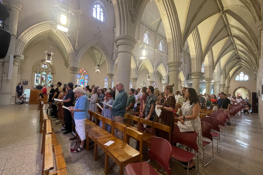 people stand in the pews of St Stephen's Cathedral in Brisbane's CBD.