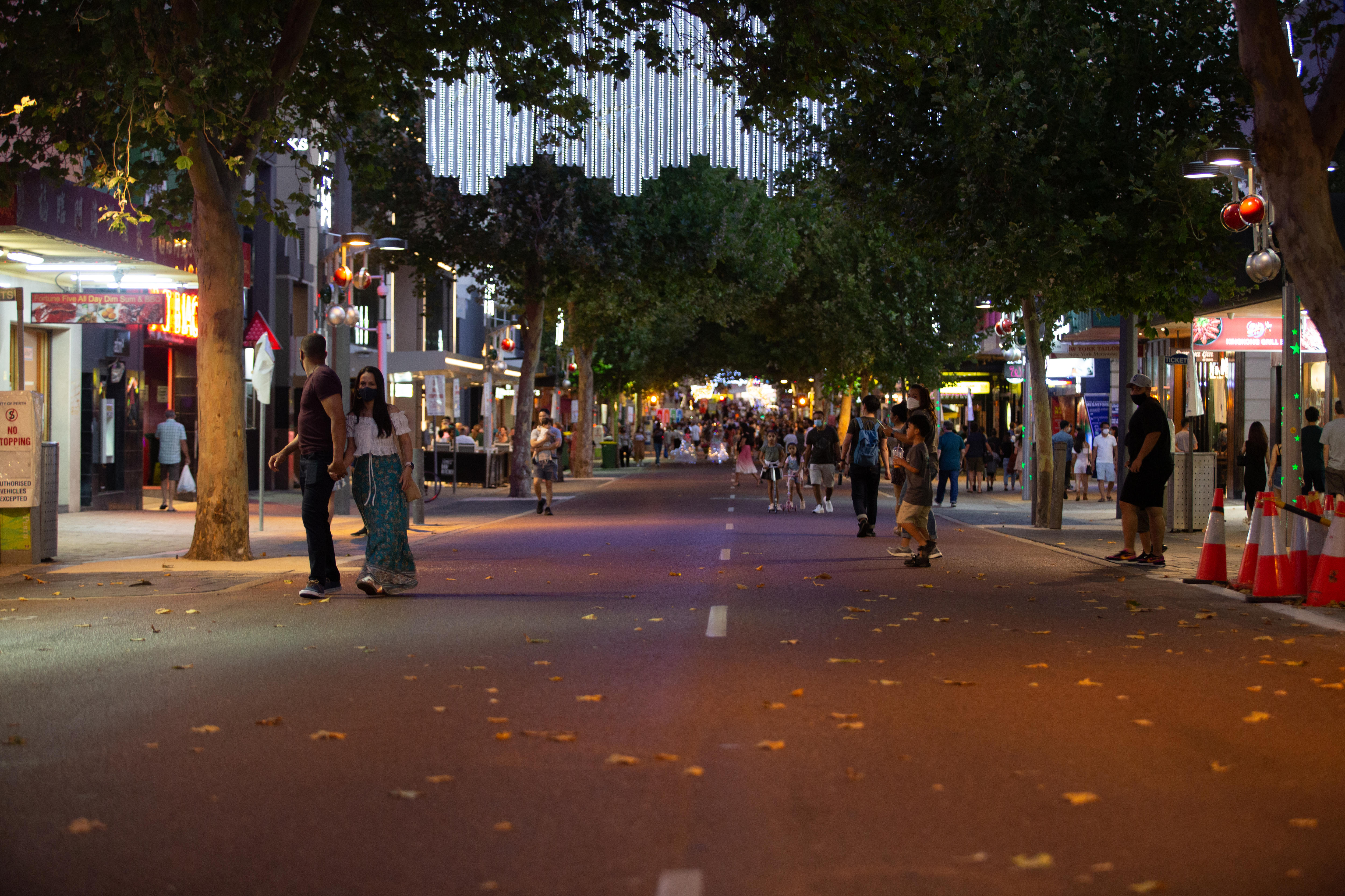 A street full of pedestrians and diners. 