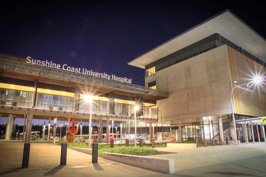 A modern hospital building, lit up at night.