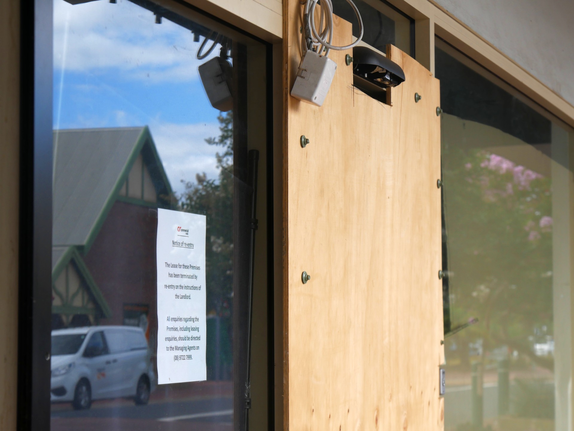 Una puerta tapiada y un aviso en una ventana.