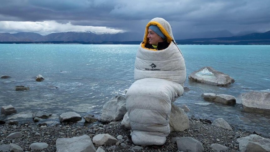 An athlete keeps warm wrapped in a sleeping bag during an ultra-marathon