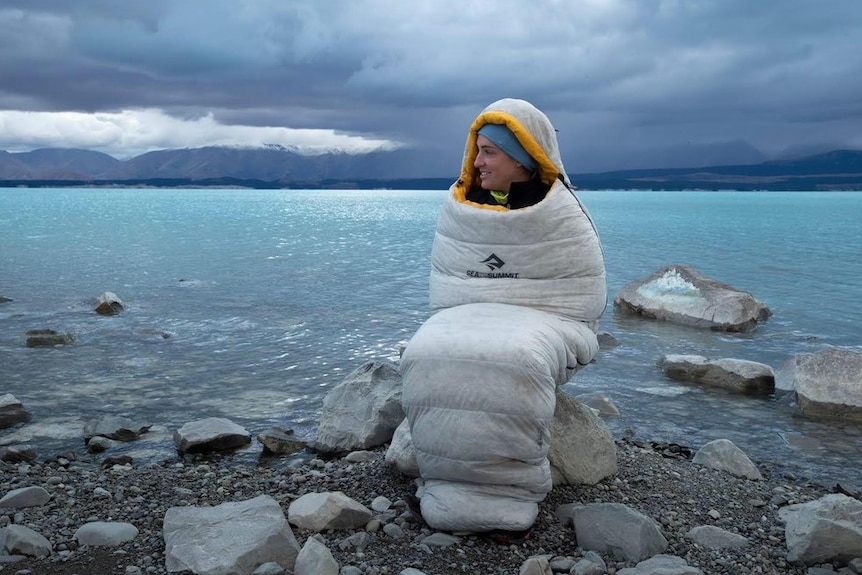 An athlete keeps warm wrapped in a sleeping bag during an ultra-marathon