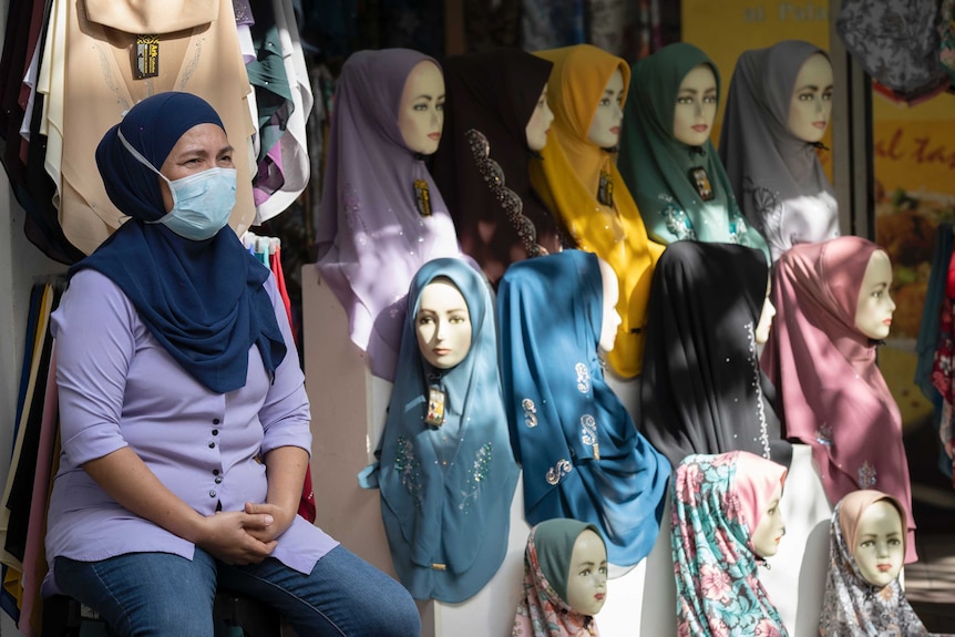 A shop vendor wearing a face mask waits for customers at her headscarves shop in Kuala Lumpur.