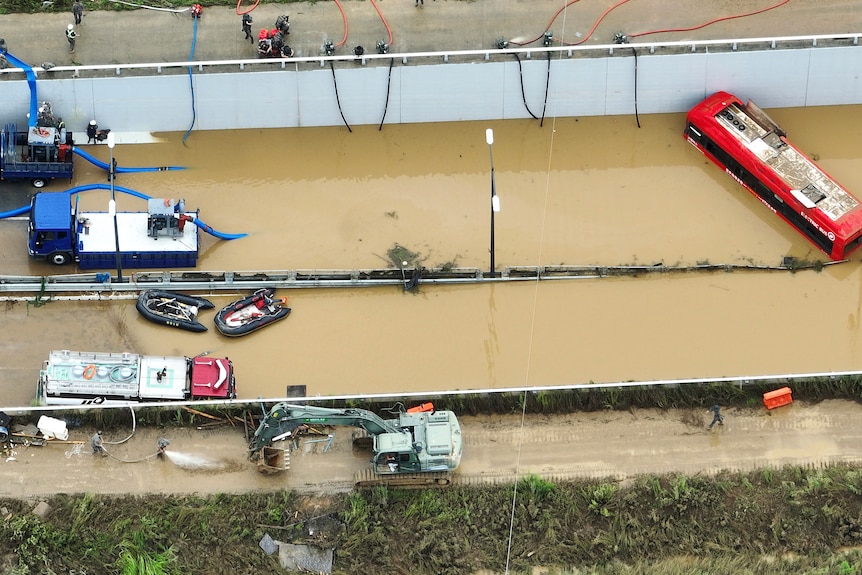 Rescuers work to search for survivors along a road submerged by floodwaters.
