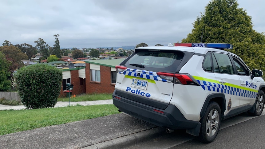 a police car parked outside a red brick house 