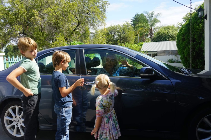 Victoria Fletcher waves to her three grandchildren through the closed window of her car, parked in the driveway.