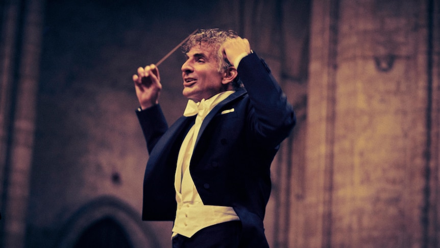 Bradley Cooper in an exuberant pose as conductor Leonard Bernstein in the film Maestro.