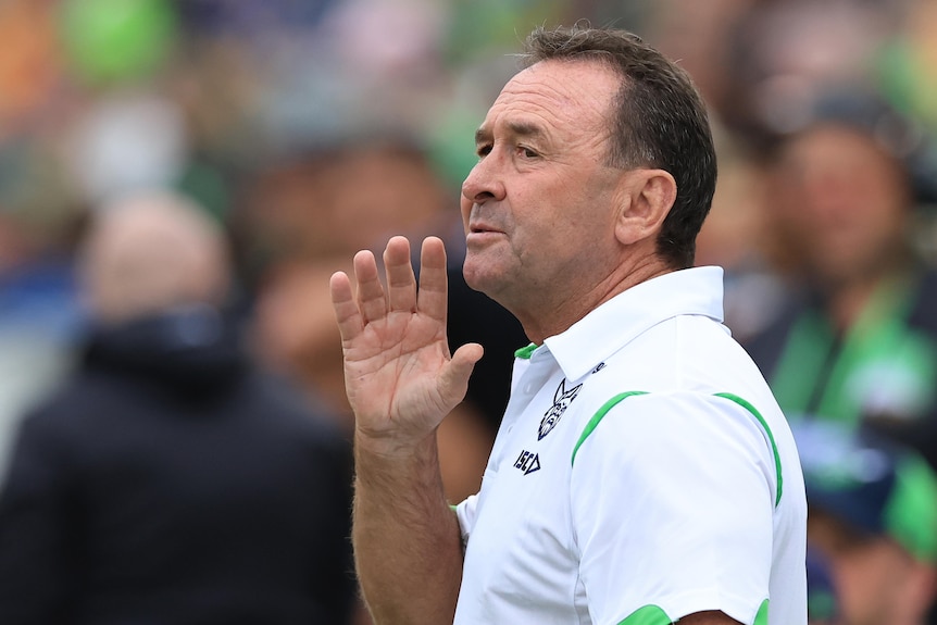 Canberra Raiders coach Ricky Stuart holds his hand to his face during an NRL game against Wests Tigers.