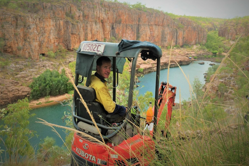 man in a bobcat looking back at camera with a dramatic gorge view beyond