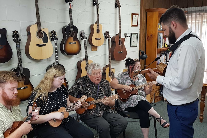 A group of people learning to play ukulele