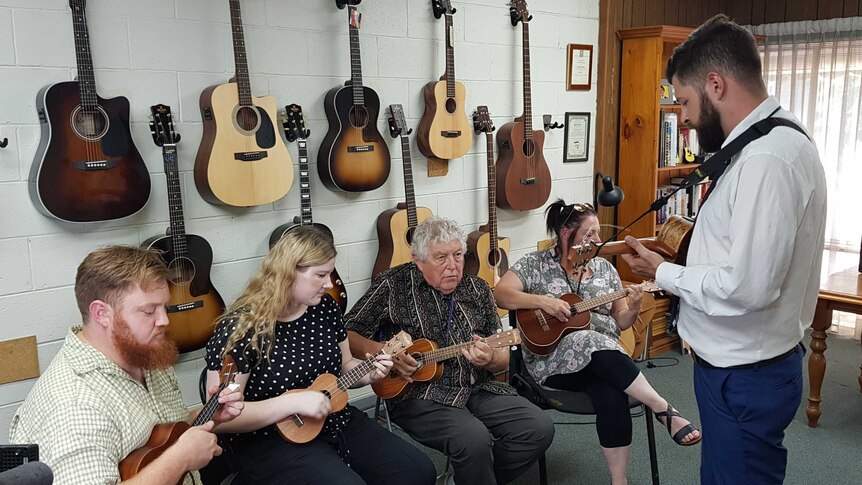 A group of people learning to play ukulele