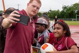 Man in maroon shirt takes selfie with young female fan