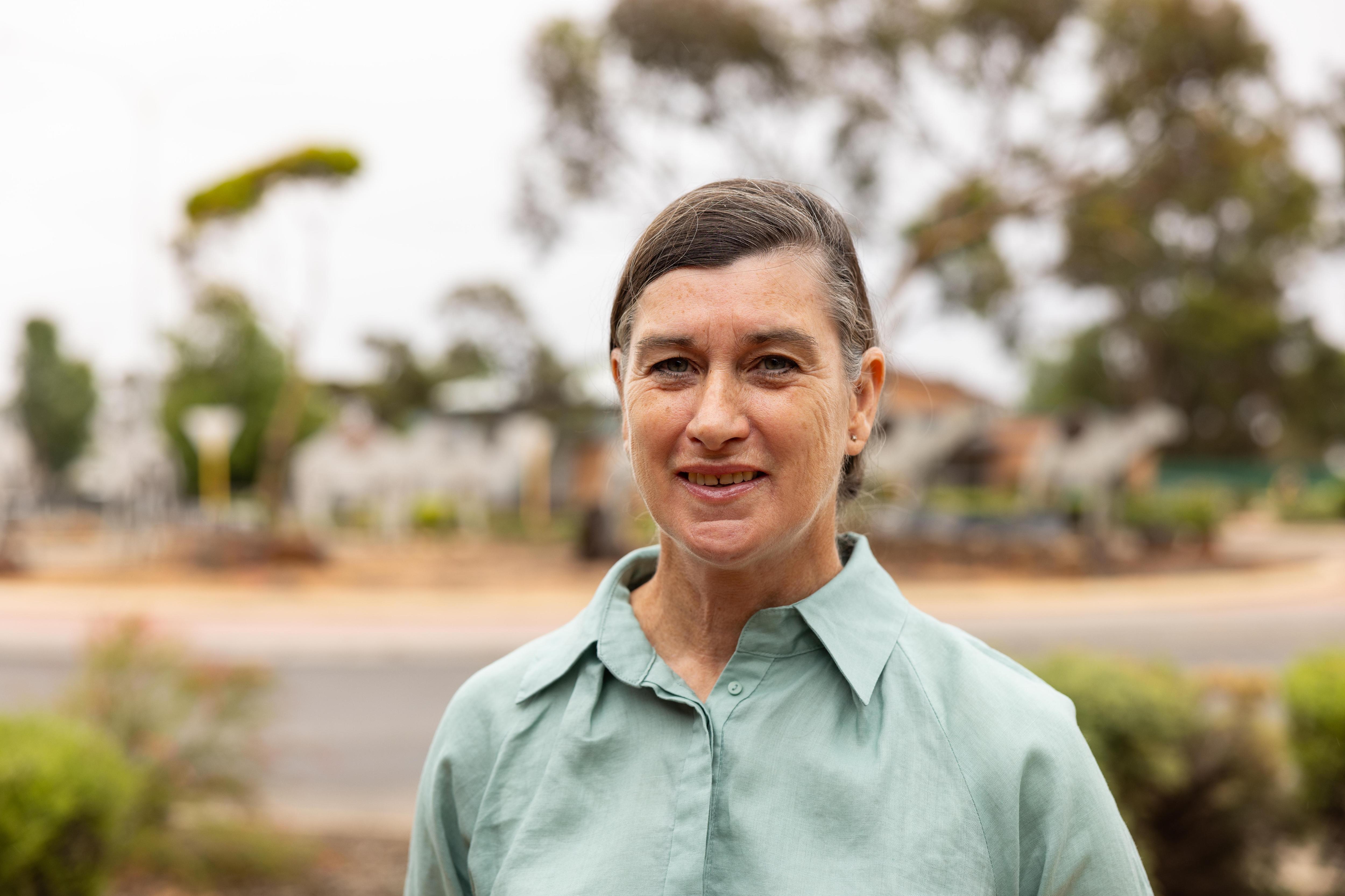 Ella usa un top verde y se encuentra junto a la rotonda de cámaras de hojalata de la ciudad