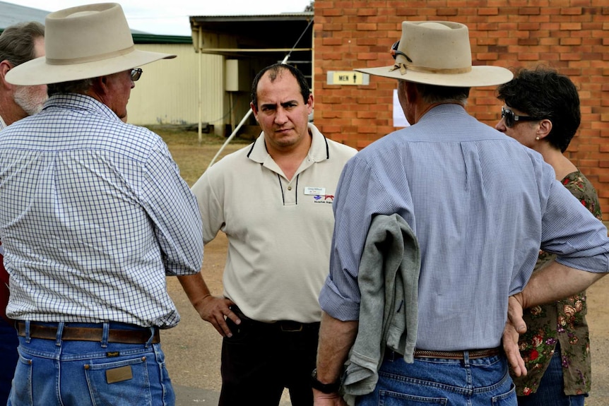 Greg Misfud looking very serious as he talks to three men and a woman.