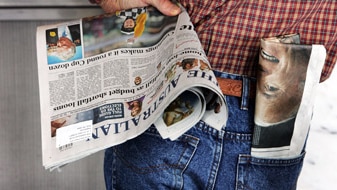 A man holding The Australian newspaper