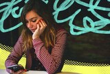 Young woman looking at phone and looking concerned with distressed illustrated background