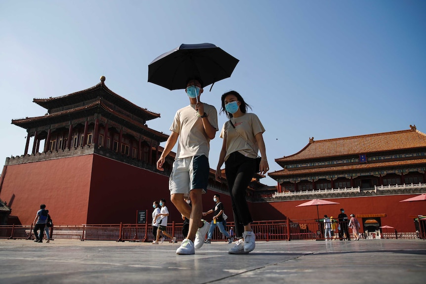 A couple wearing masks walking inside the Forbidden City in Beijing.