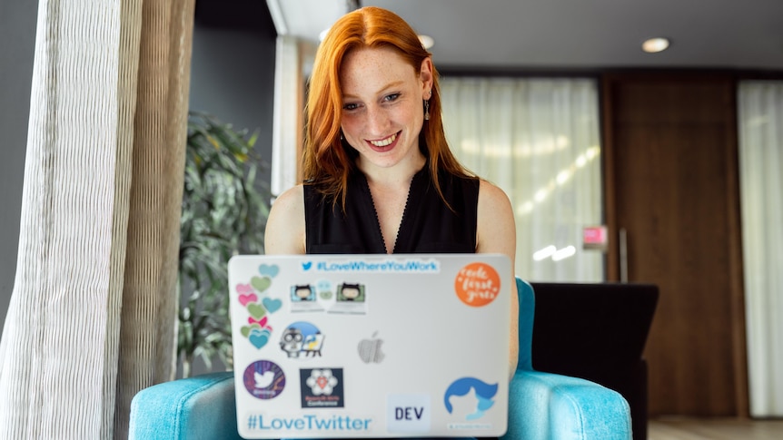 Woman looking at laptop while sitting on her lounge in a story about improving work life in 2021.