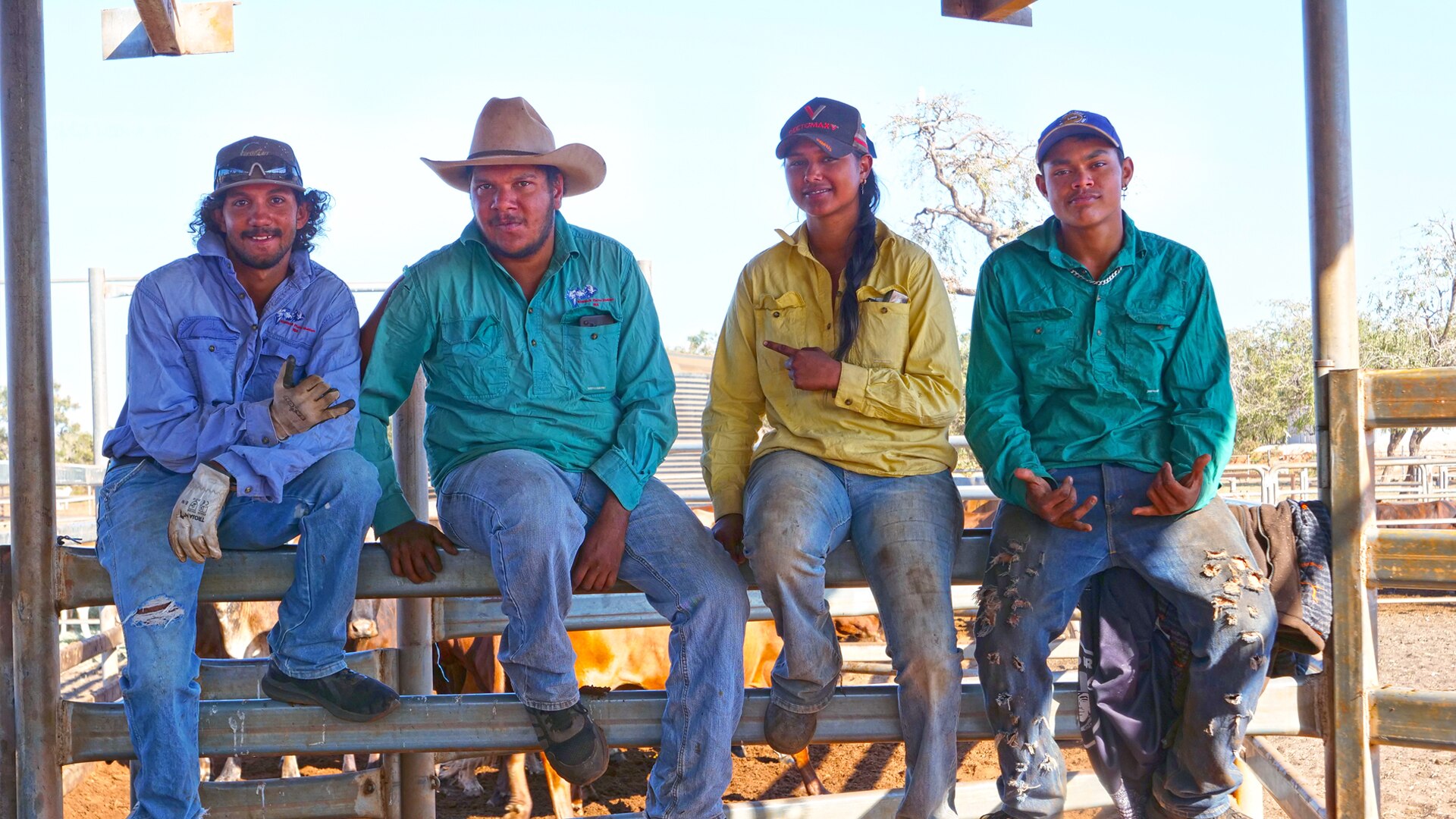 Four young people sit on a rail smiling at the camera