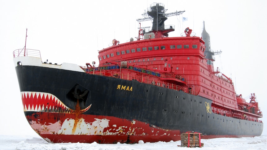 A red icebreaker ship sailing through sheet ice. 