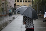 A commuter in Sydney this morning cowering from the rain.