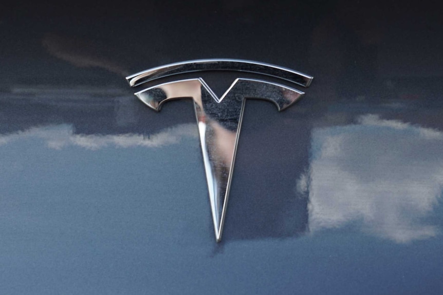 A close up of the Tesla badge on the bonnet of a car.