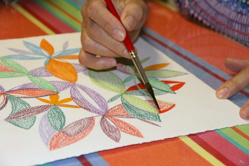 Artist adding water to watercolour pencil drawing via a paintbrush