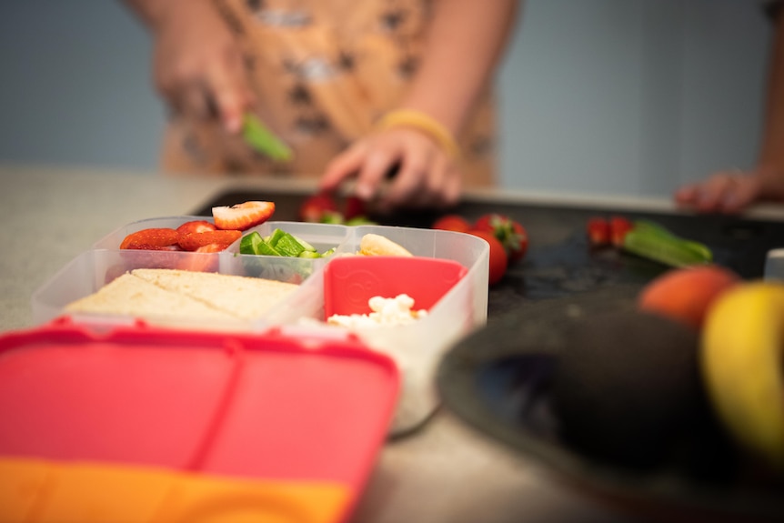 A pair of hands prepare food on a kitchen bench top