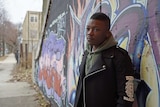 Jaymal Green stands in front of a graffitied wall