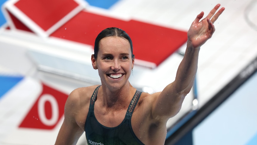 A smiling Emma McKeon of Australia waves on pooldeck after winning an Olympic gold medal in the 100m freestyle.