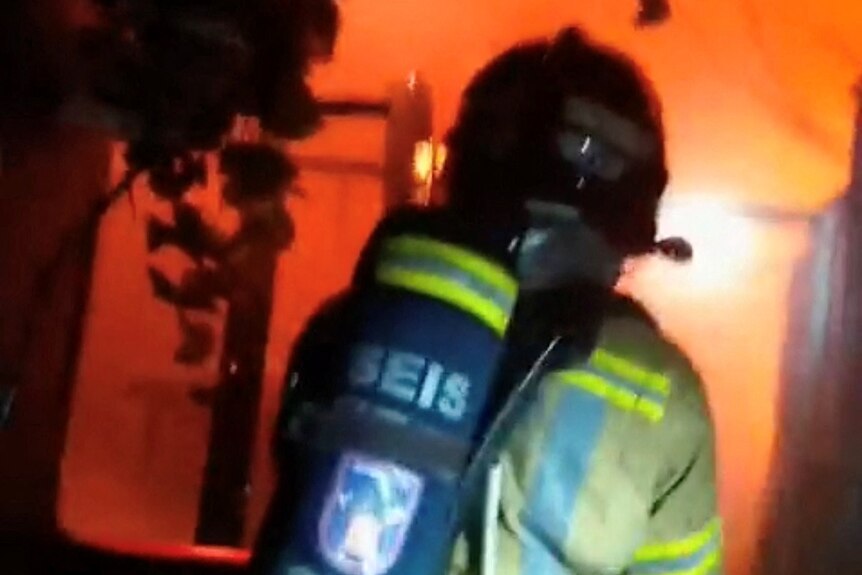 Un bombero frente a una habitación en llamas. 
