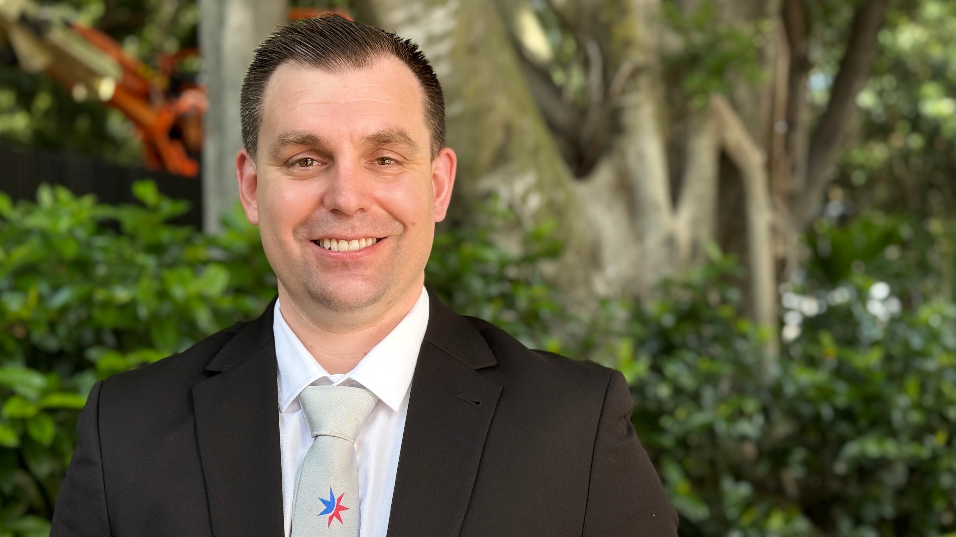 Un hombre con traje y corbata sonríe a la cámara.