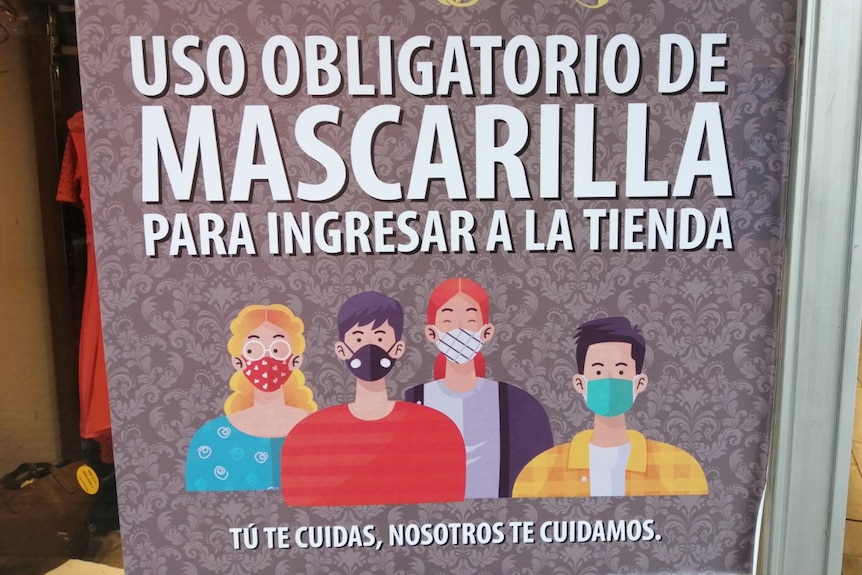 A sign in Spanish alerts customers to a store's mandatory mask policy.