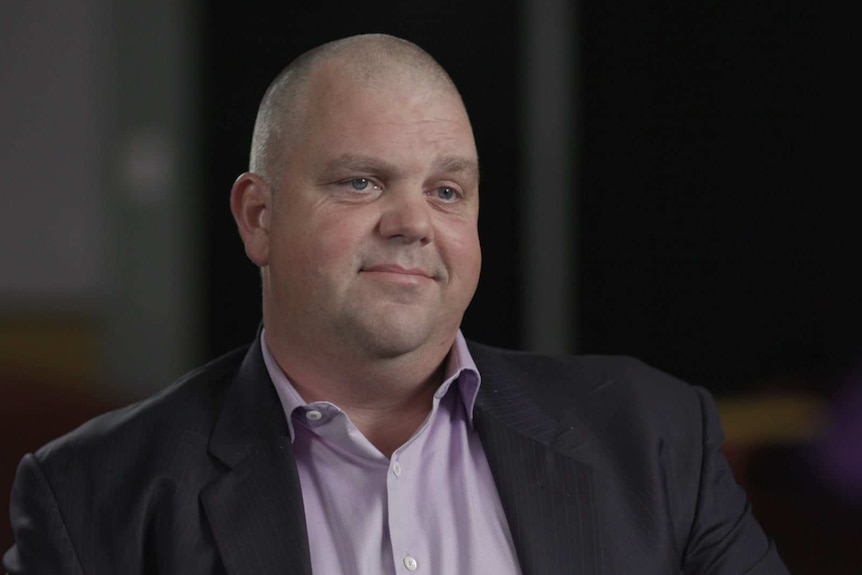 Nathan Tinkler wears a purple shirt and dark suit jacket.