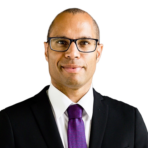 A smiling man in a black suit and purple tie.