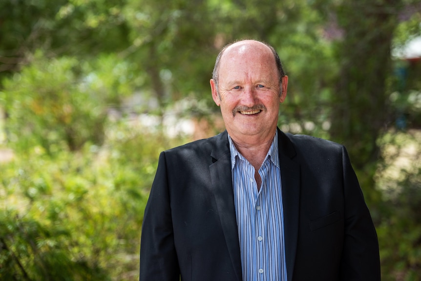 a man with a bald head and moustache smiles at the camera