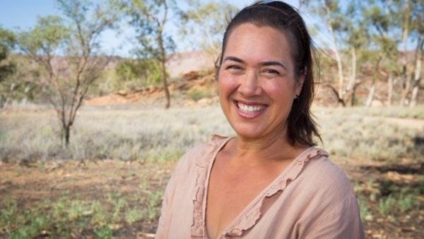 Catherine Liddle smiling in a portrait taken outdoors in arid looking bushland.
